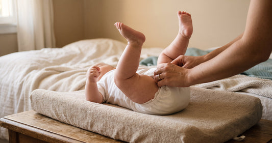 Change d'un bébé sur le tapis à langer : ajustement de la couche au niveau de la cuisse